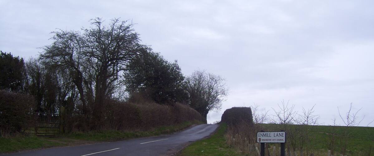 A rural road with a sign indicating Enmill Lane in Winchester City Council.