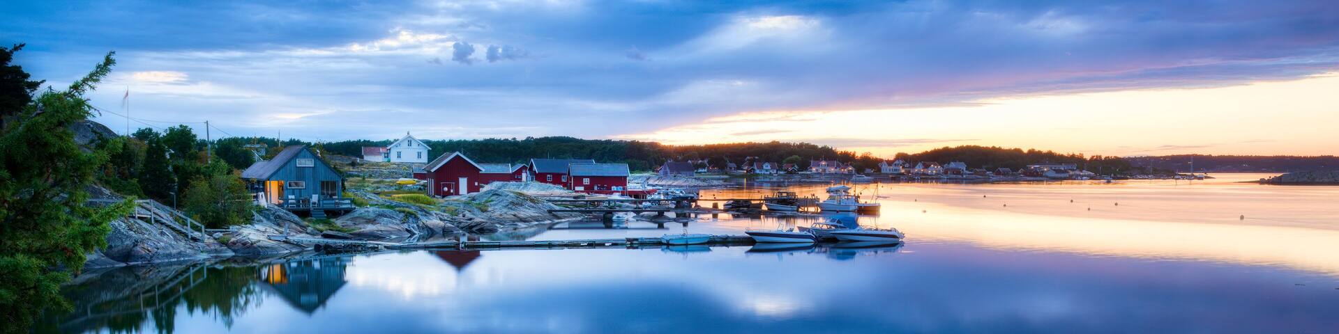 A calm lake with boats, a red house, and a dock.