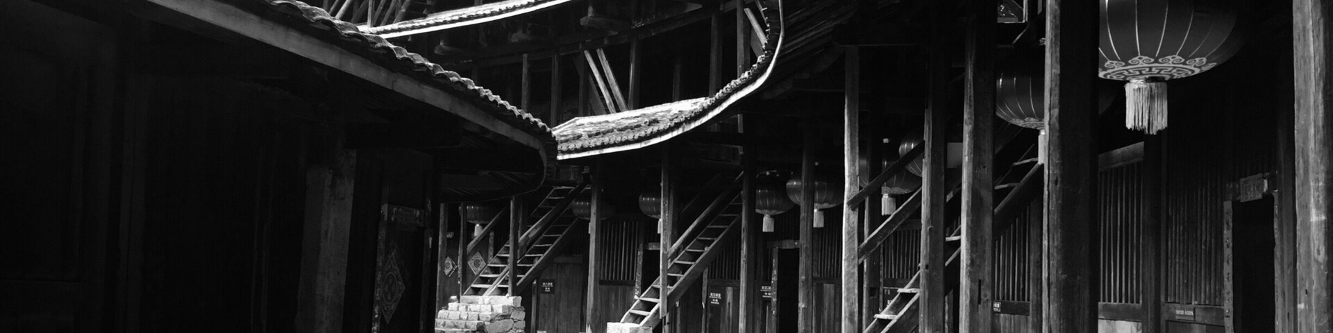 Un edificio de madera tradicional con techo curvo, escalones de piedra y faroles colgantes.