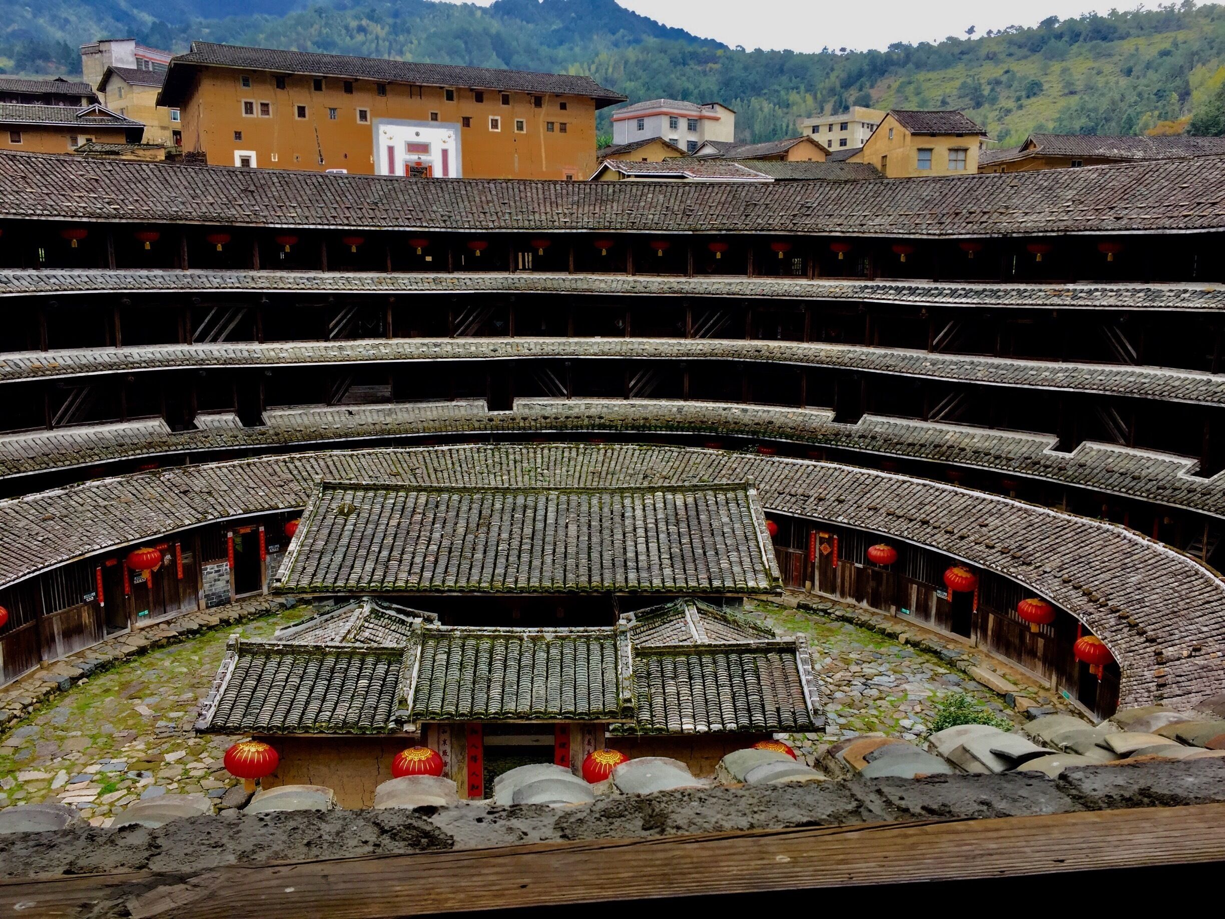 A traditional multi-tiered stone theatre with red lanterns and a central stage.