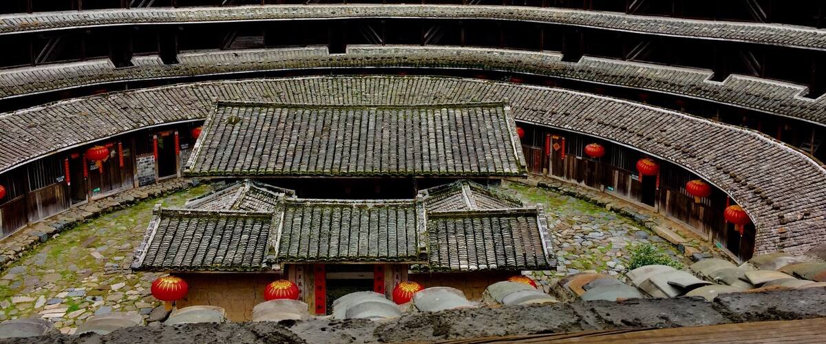 A traditional multi-tiered stone theatre with red lanterns and a central stage.