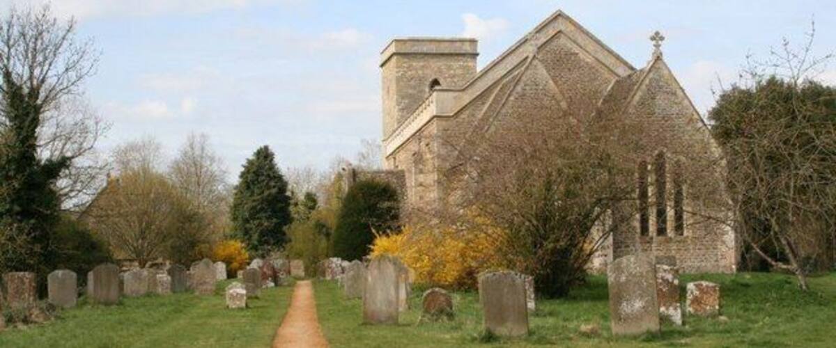 A church with a stone facade and a graveyard with headstones.