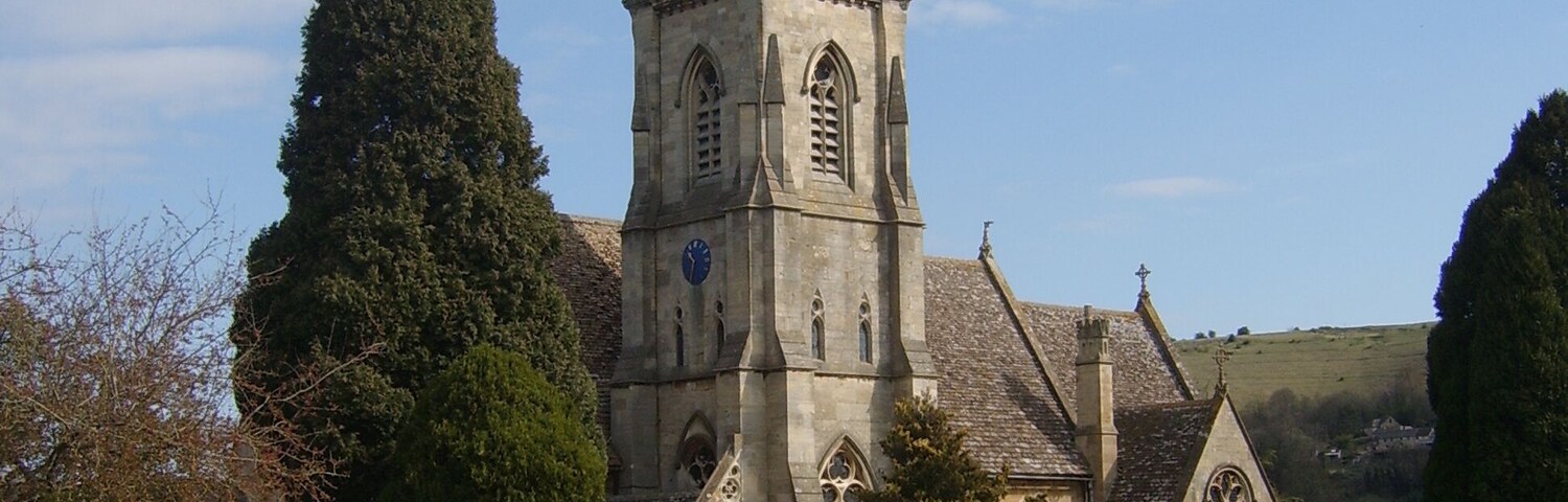 A church with a tall spire and a cemetery in the foreground.
