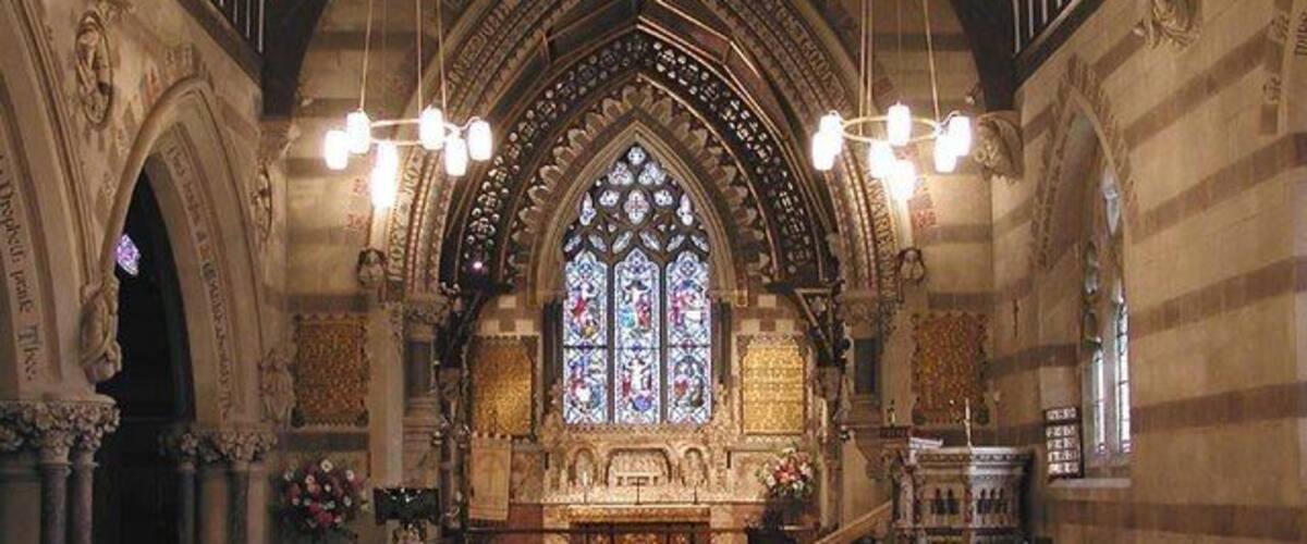 An interior of a church with Gothic architecture, including pointed arches and stained glass windows.