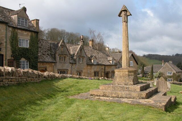 A stone cross in a village with stone houses.