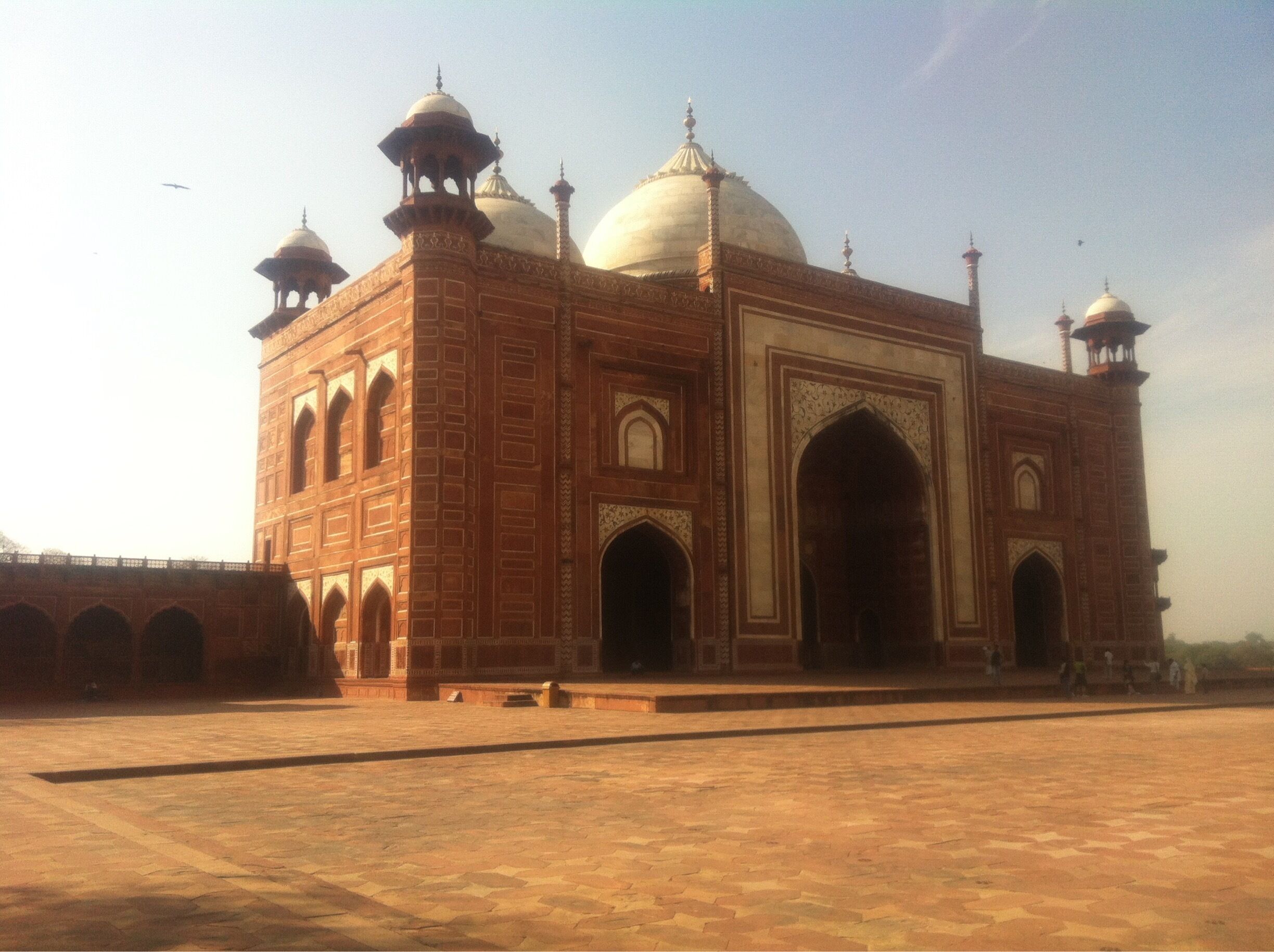 A large, historic building with domes and arches, surrounded by a paved area.