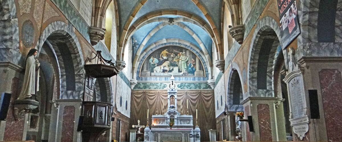 A cathedral interior with high vaulted ceilings, arched windows, and a central altar.