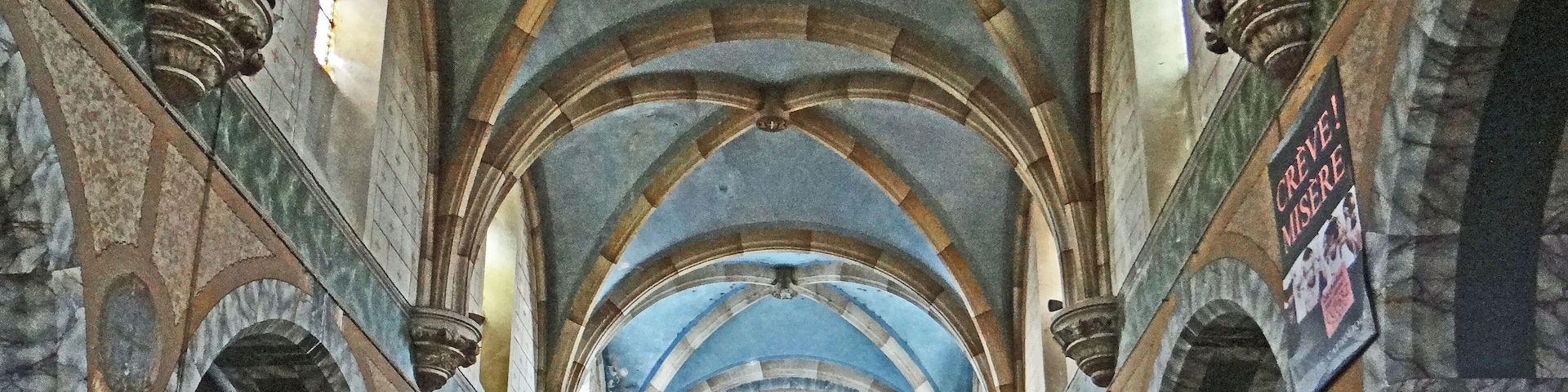 A cathedral interior with high vaulted ceilings, arched windows, and a central altar.