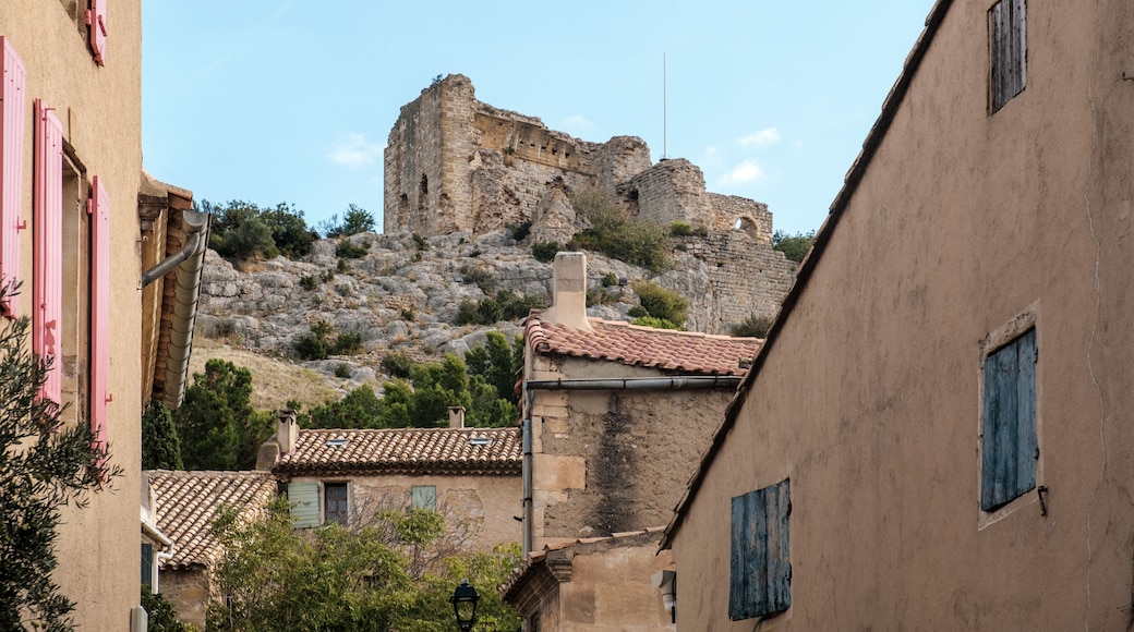 A historic stone fortress atop a hill, surrounded by traditional buildings with terracotta roofs and shutters.
