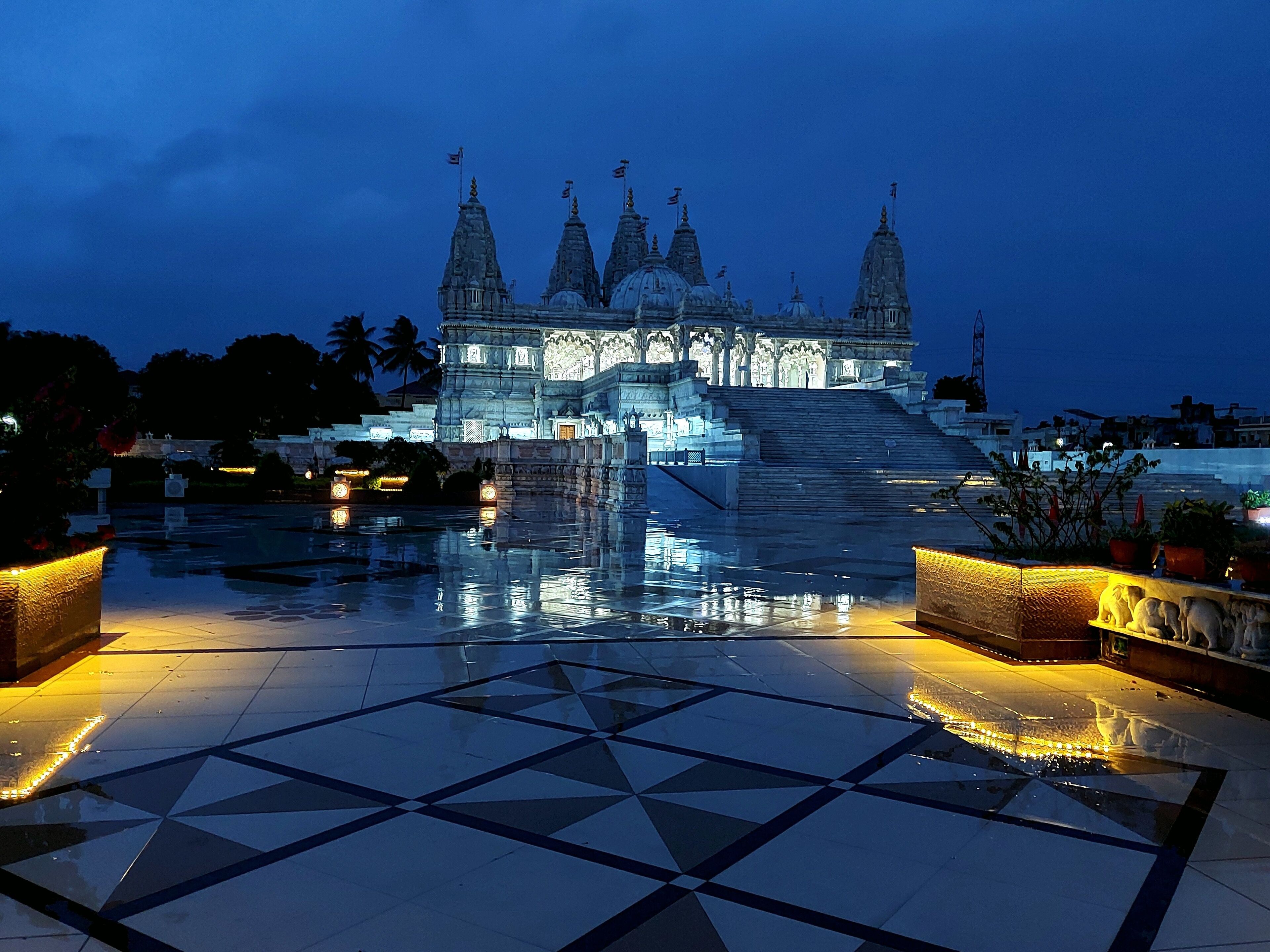 A temple with multiple spires and a reflective water feature in the foreground.