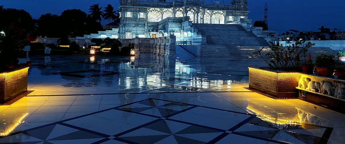 A temple with multiple spires and a reflective water feature in the foreground.