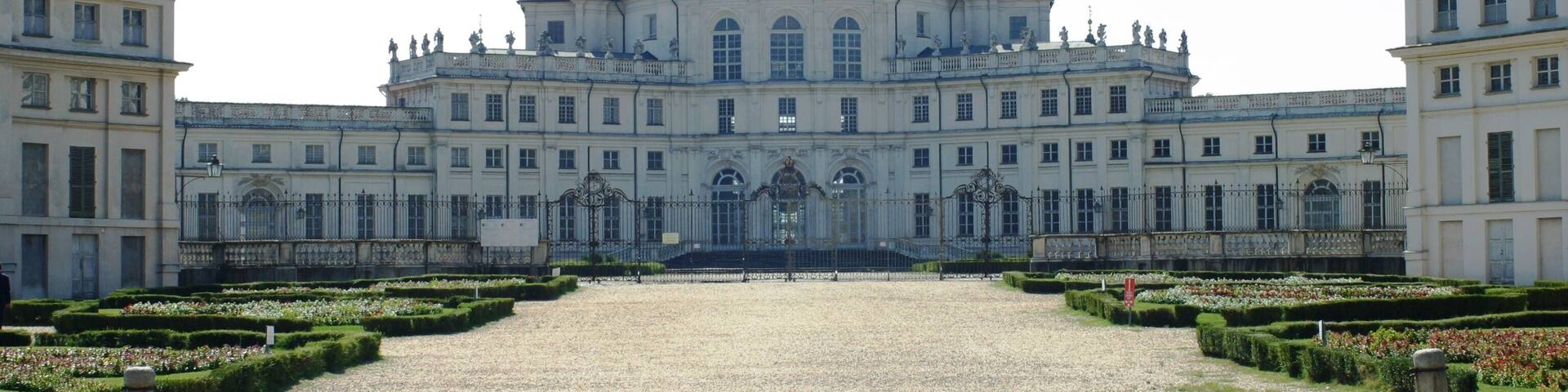 A grand palace with a symmetrical facade, a central dome, and a gravel courtyard.