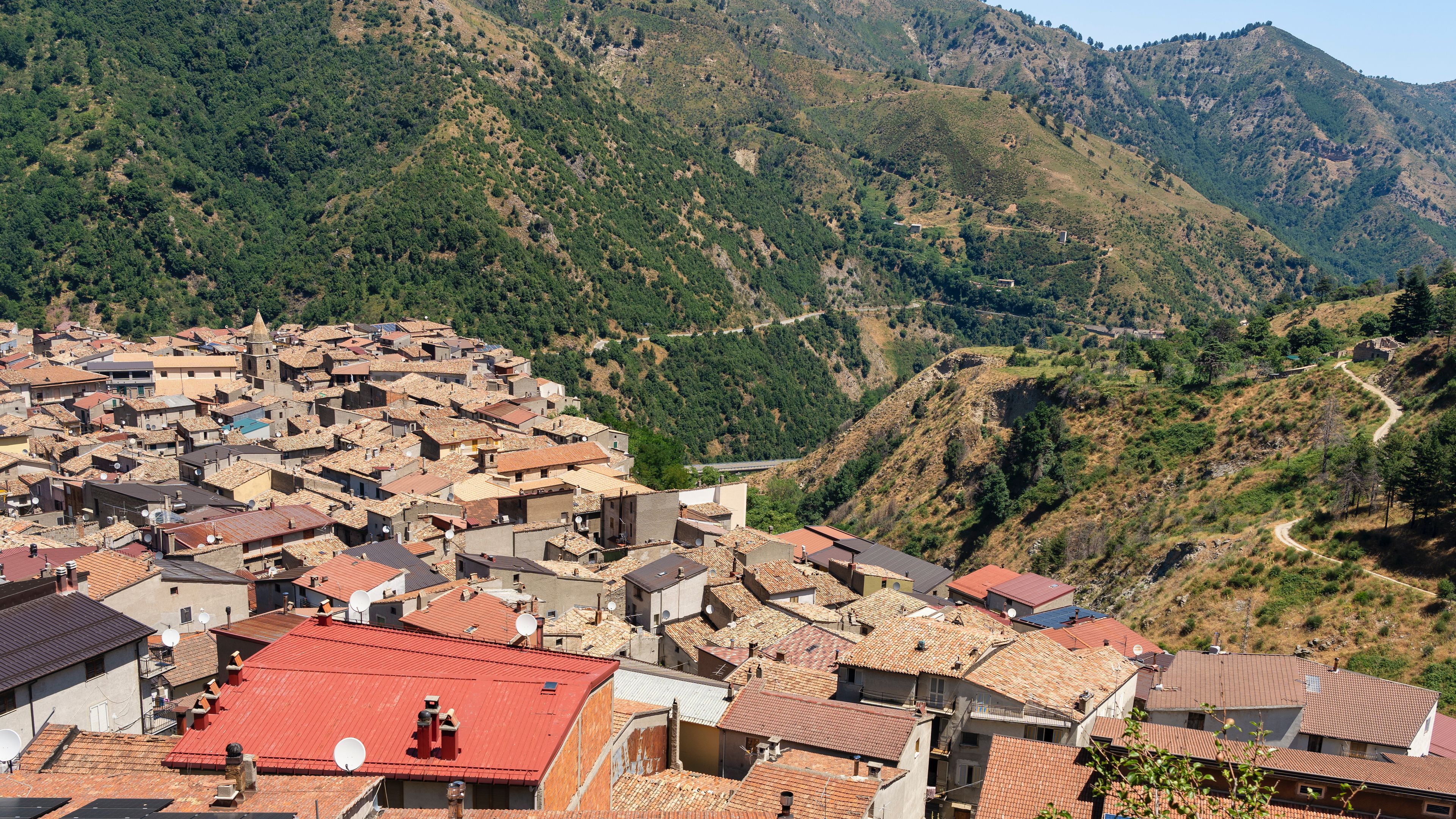 Un village de montagne aux bâtiments aux toits de tuiles rouges, niché dans une vallée.