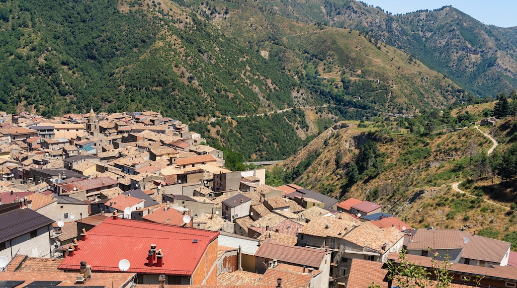 Un village de montagne aux bâtiments aux toits de tuiles rouges, niché dans une vallée.