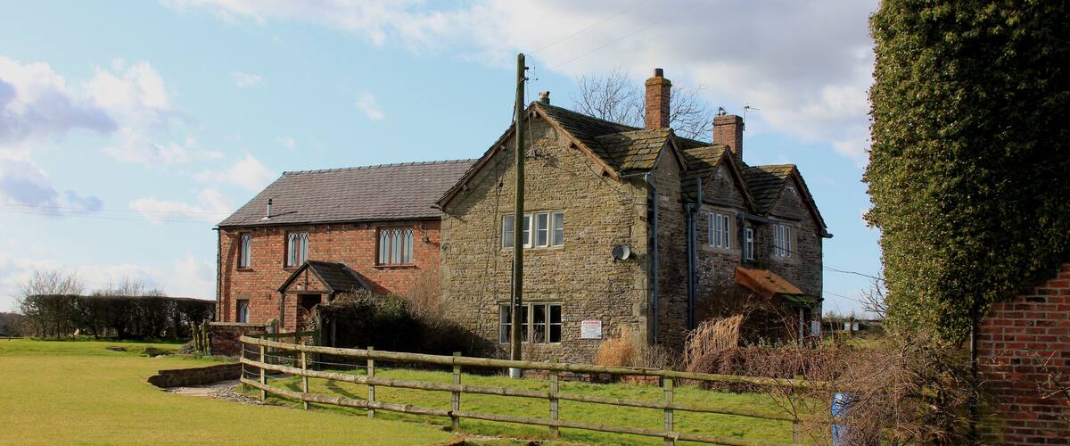 A stone house with a wooden fence in a rural setting.