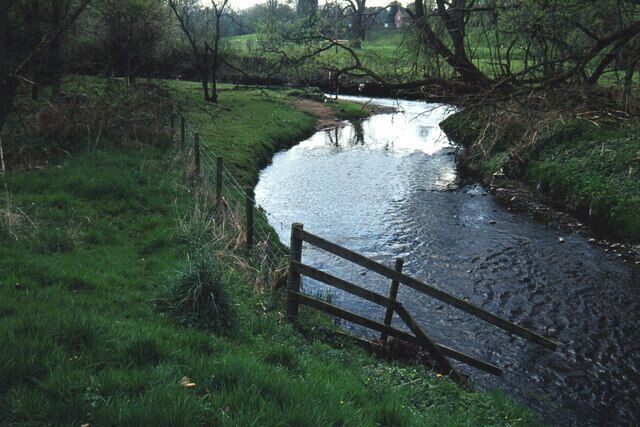 River Bollin below Prestbury. Looking upstream towards Prestbury. A footpath leads along the right hand bank of the river from this point into Prestbury.