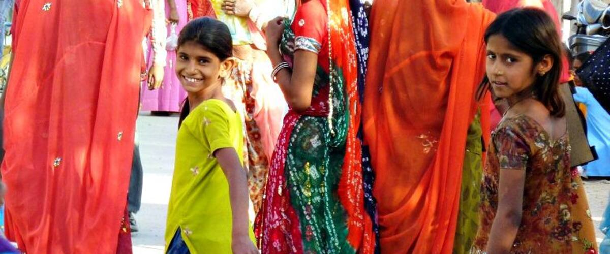 A group of people, including children and women, in traditional colorful attire.
