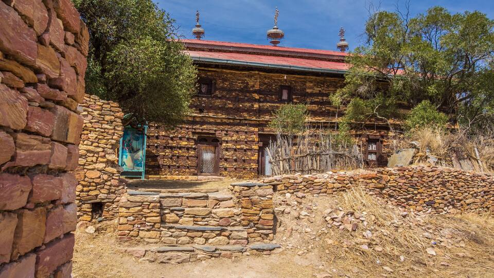 A traditional stone building with a red roof and decorative domes.