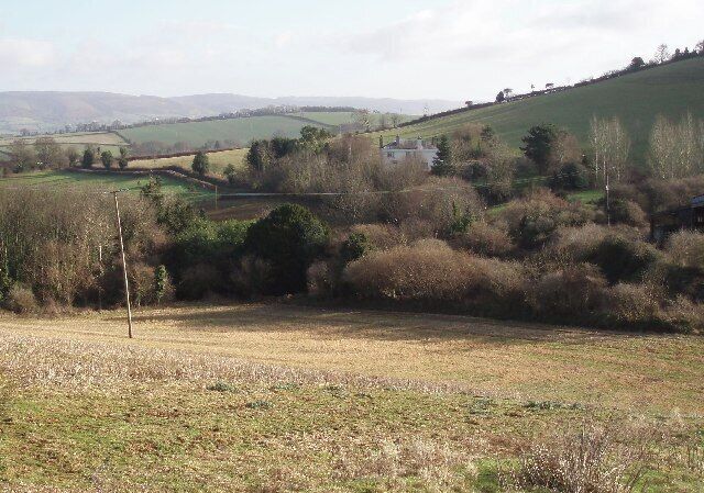 White house at Birchanger. Birchanger is tucked into a fold in the hills and invisible below and to the left of the house. The closer you get to it, the less you can see of it!