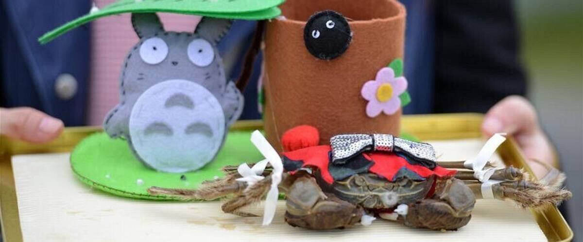 A person holding a tray with a felt animal head, a felt cup with a flower, and a felt horse with a saddle.