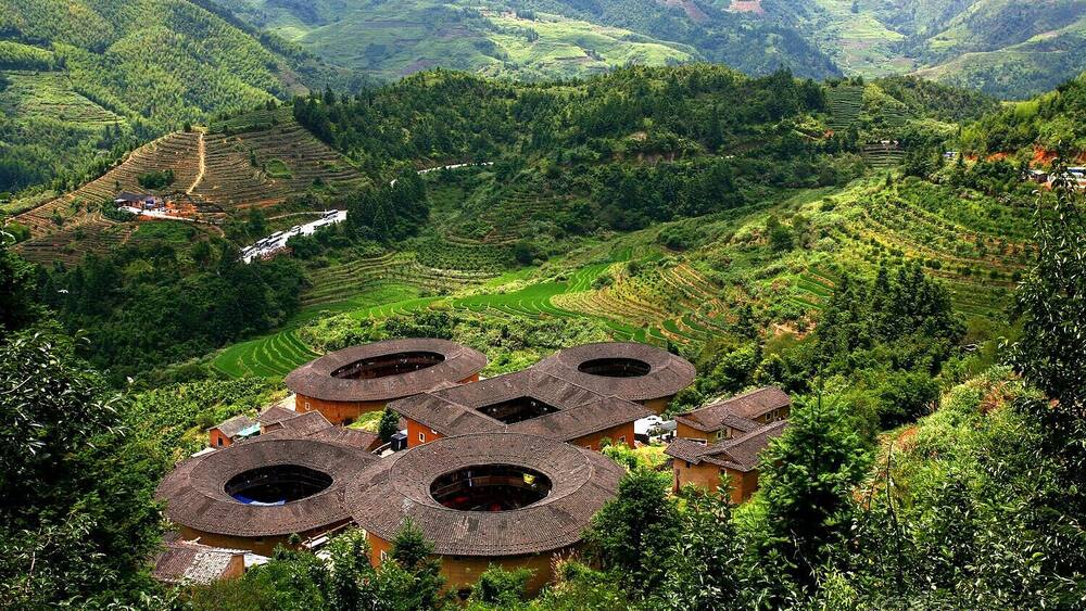 Terraced fields, traditional houses with circular roofs, and lush green hills.