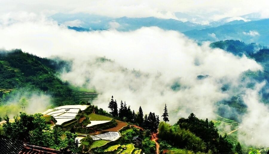 A mountainous landscape with terraced fields and a village nestled among the hills.