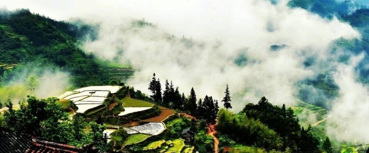 A mountainous landscape with terraced fields and a village nestled among the hills.
