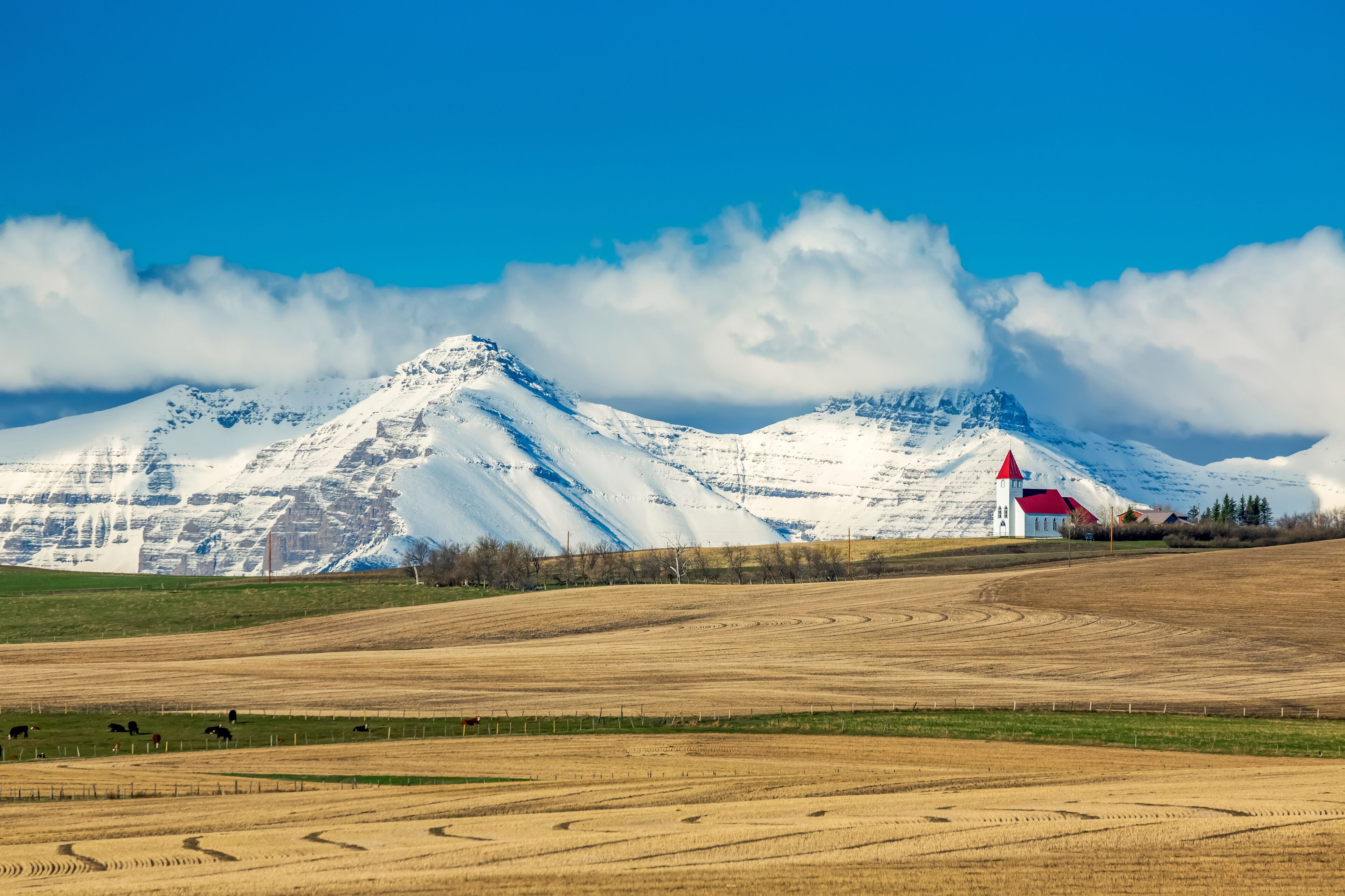A snow-covered mountain range with a red-roofed building in the foreground.