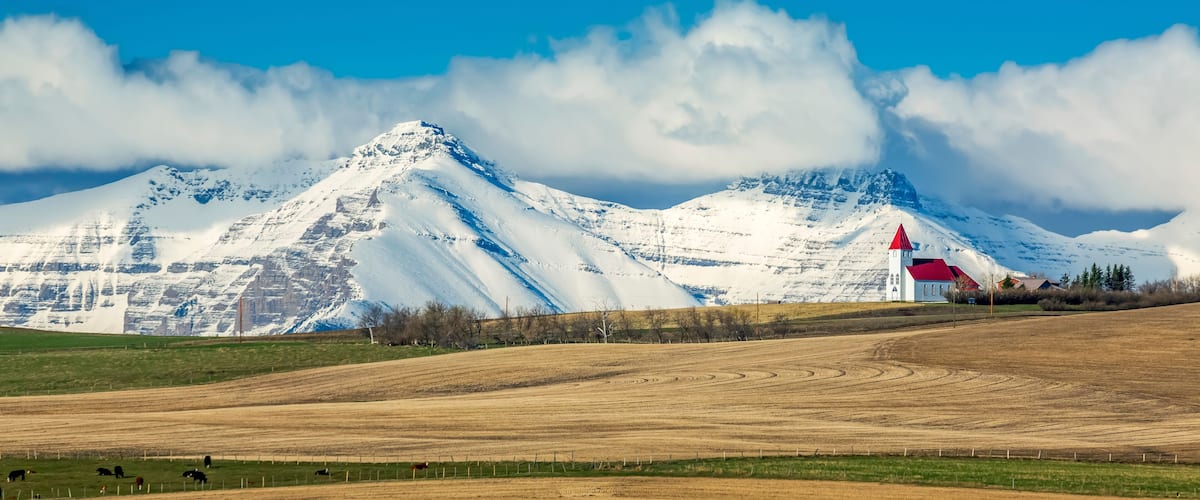 A snow-covered mountain range with a red-roofed building in the foreground.