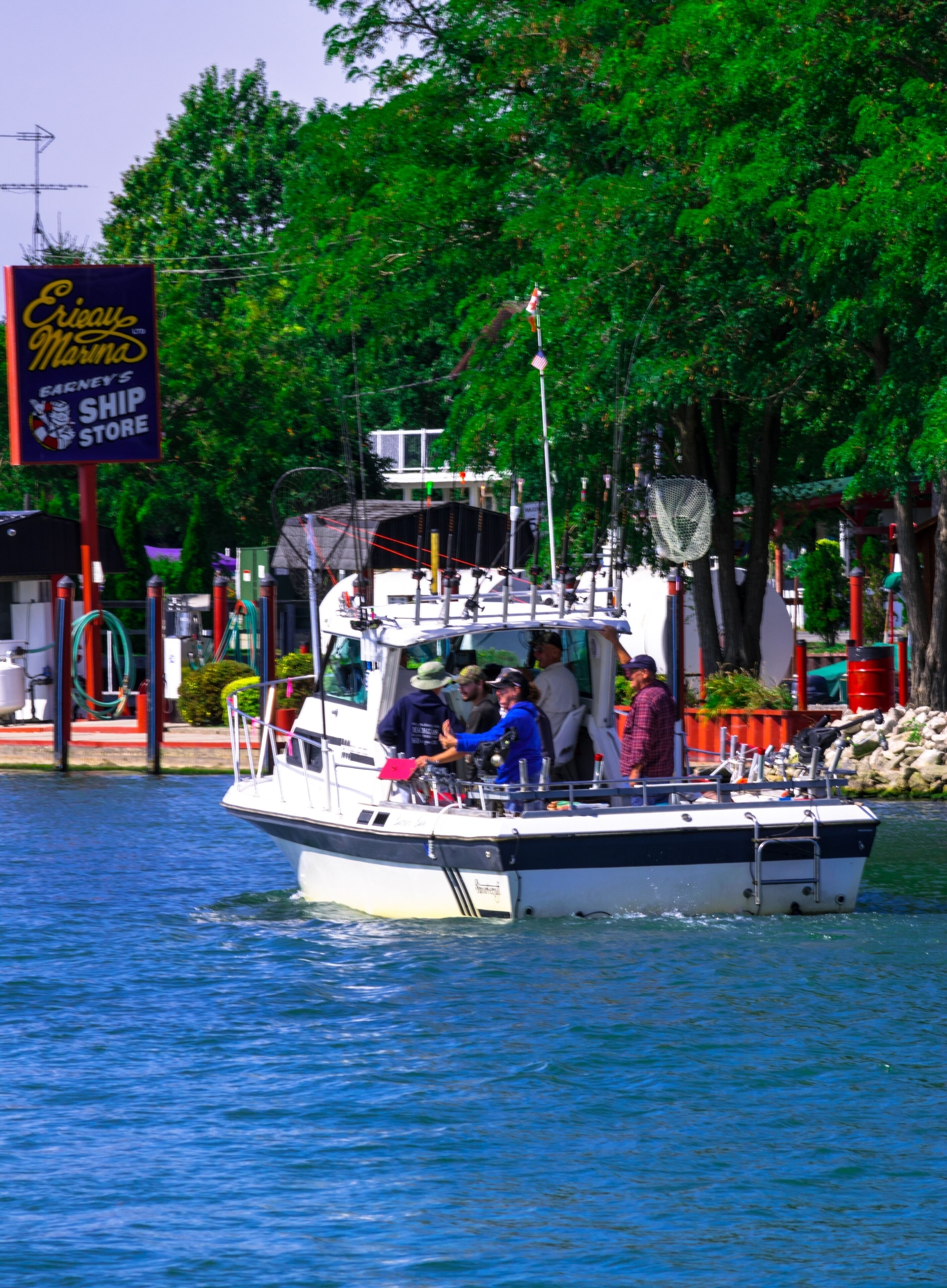 A boat with people on it near a dock with a sign for a ship store.