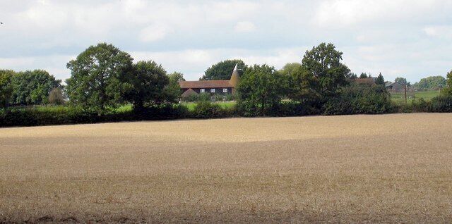 A rural landscape with a field, a house, and trees.
