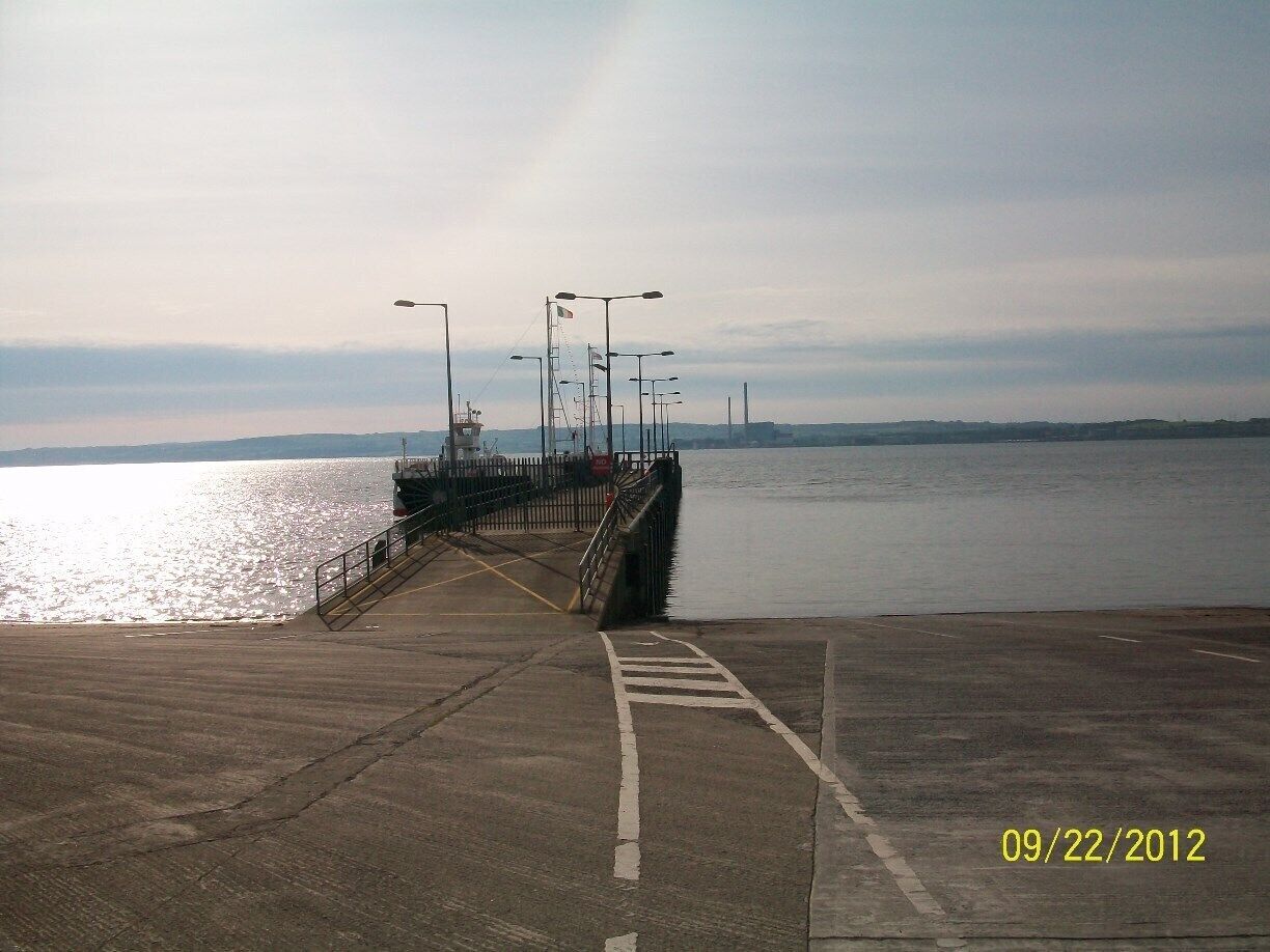 A pier extending into calm water with a clear sky.