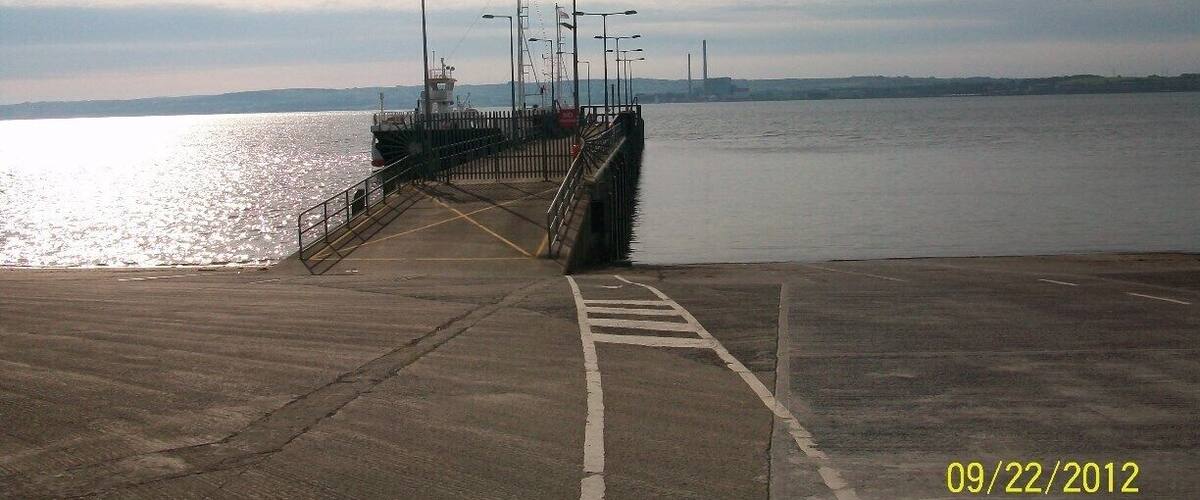 A pier extending into calm water with a clear sky.