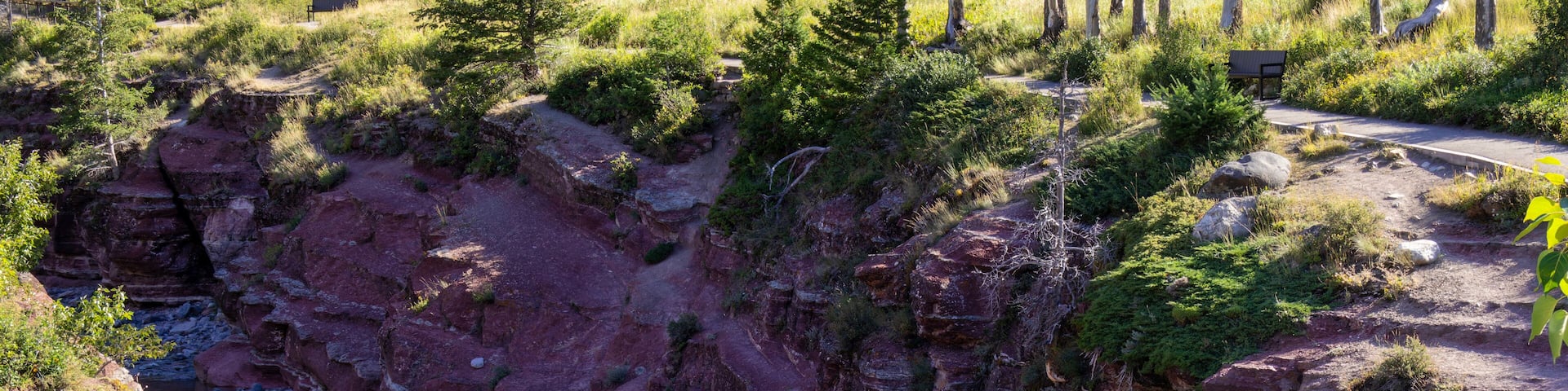 Red Rock Canyon in Waterton lake national park of Alberta, Canada, a natural gorge where brilliant red and green bedrock layers contrast with clear rushing mountain water.