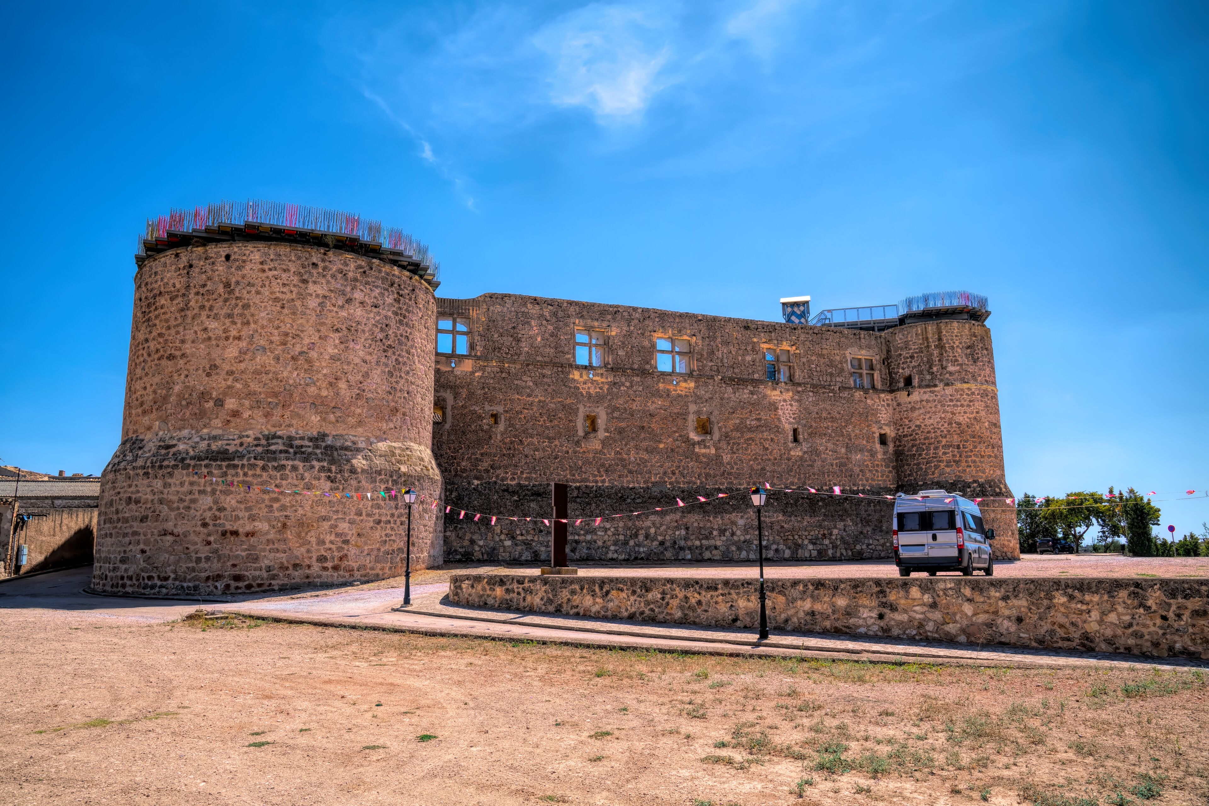 A historic stone castle with a round tower and a paved courtyard.