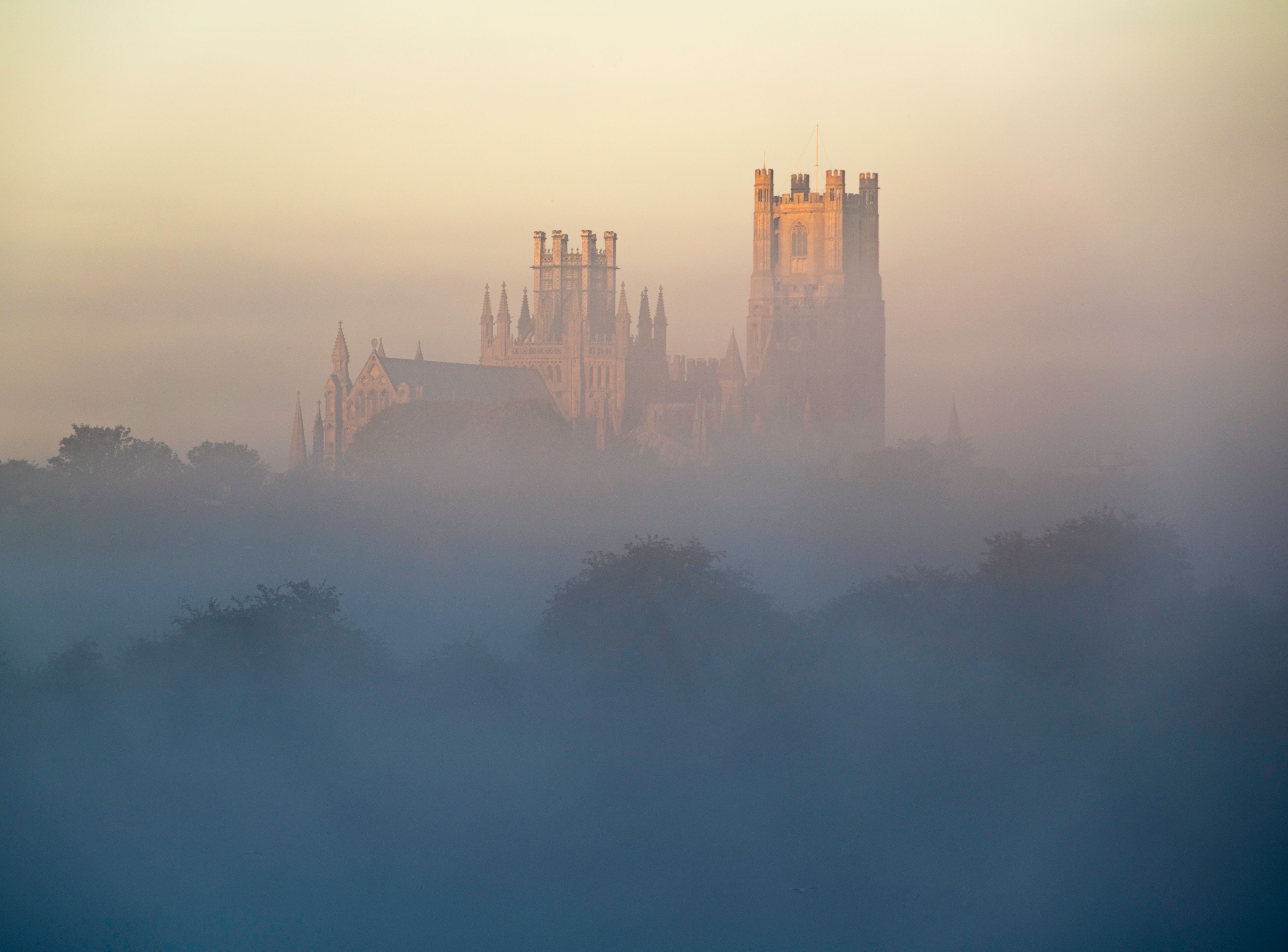 A historic castle with multiple towers and spires, surrounded by a misty landscape.