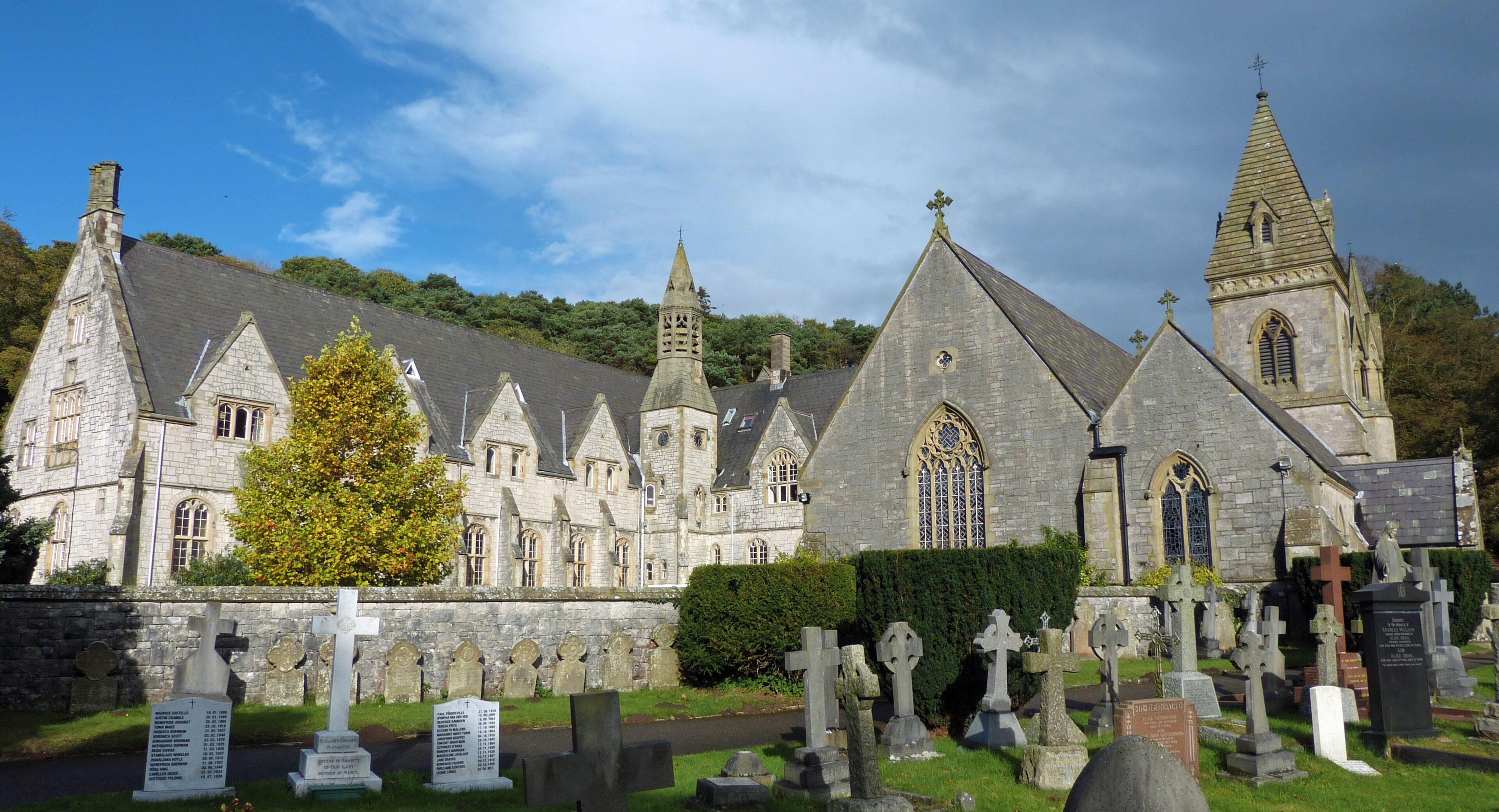 A historic stone church with a large bell tower and a cemetery in front.