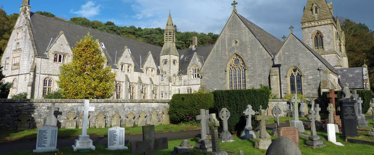 A historic stone church with a large bell tower and a cemetery in front.