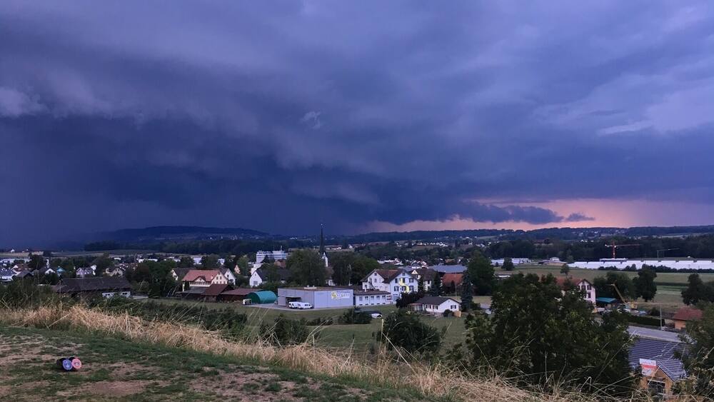 Ländliche Landschaft mit Kirche, Häusern und einem Feld.
