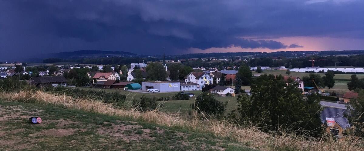 A rural landscape with a church, houses, and a field.