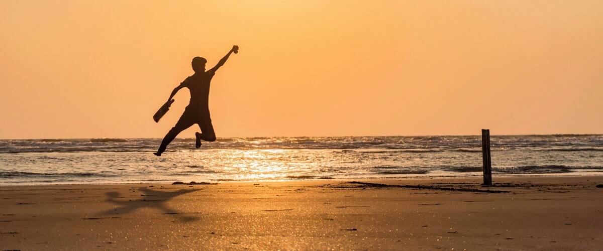 A silhouette of a person running on a beach at sunset.