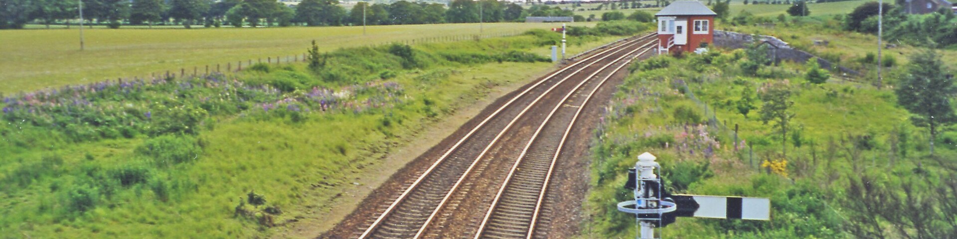 Site of former Inverkeilor station. View SW, towards Arbroath, Dundee etc.: ex-NBR Edinburgh/Glasgow - Dundee - Arbroath - Montrose - Aberdeen main line. Nothing is left of the station, which closed 22/9/30, but there is what appears to be a signalbox - ?? converted into a house.