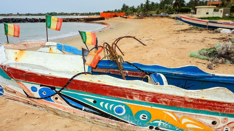 A colorful boat with a decorative design on a sandy beach.