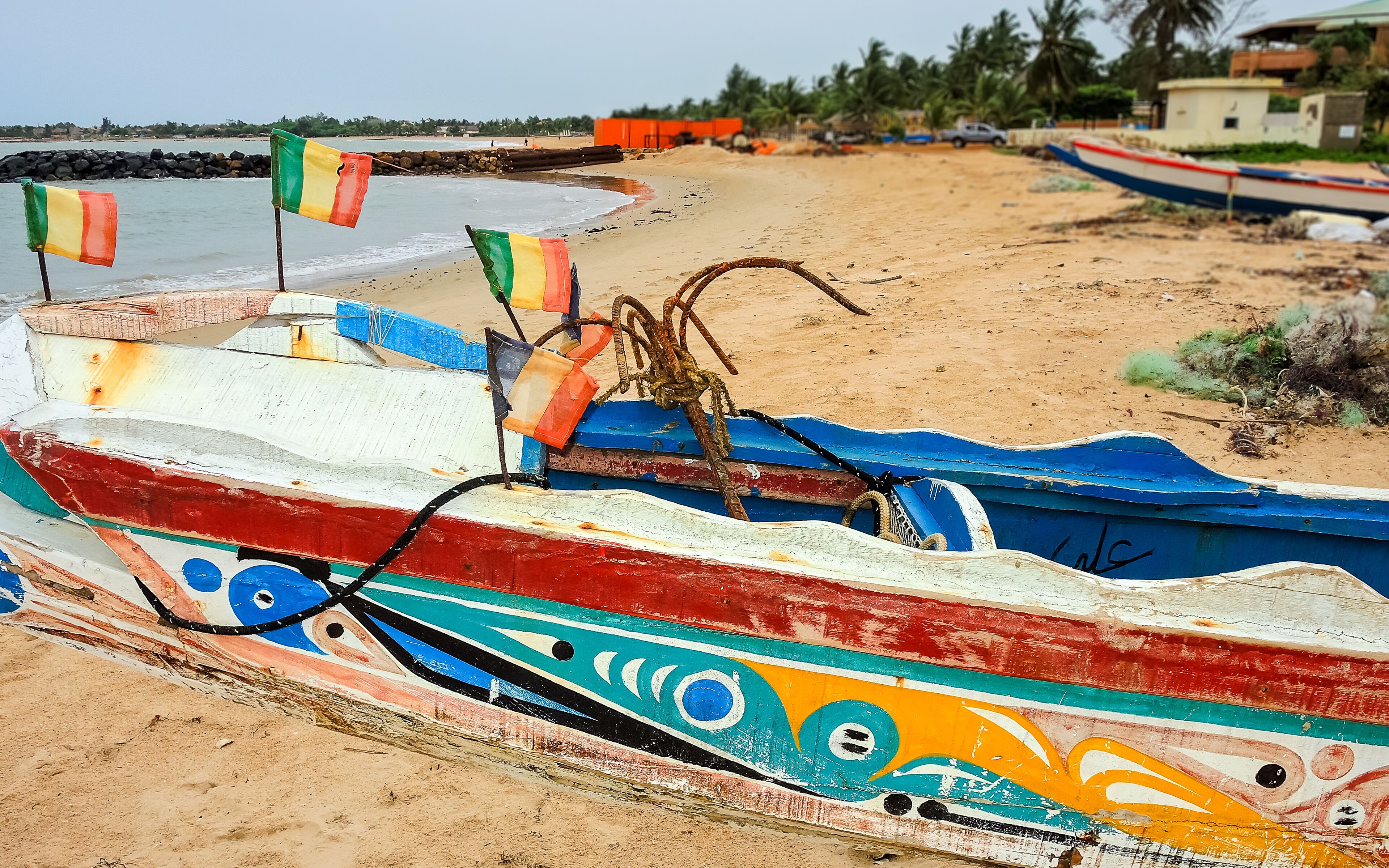 A colorful boat with a decorative design on a sandy beach.