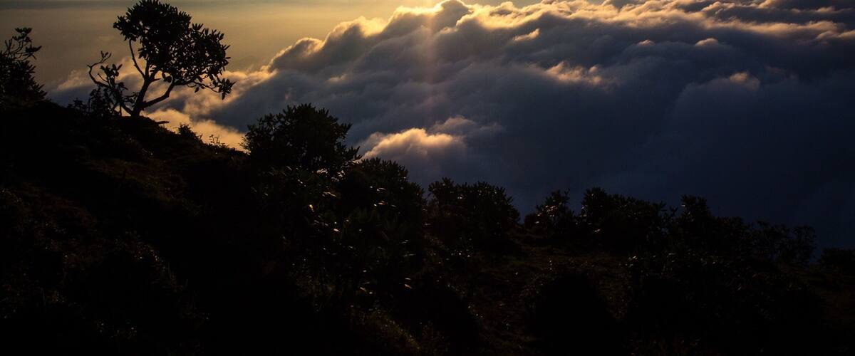 A sunrise over a mountain range with clouds below.