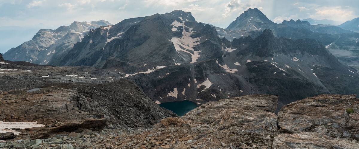 A rugged mountain landscape with rocky terrain and a small lake.