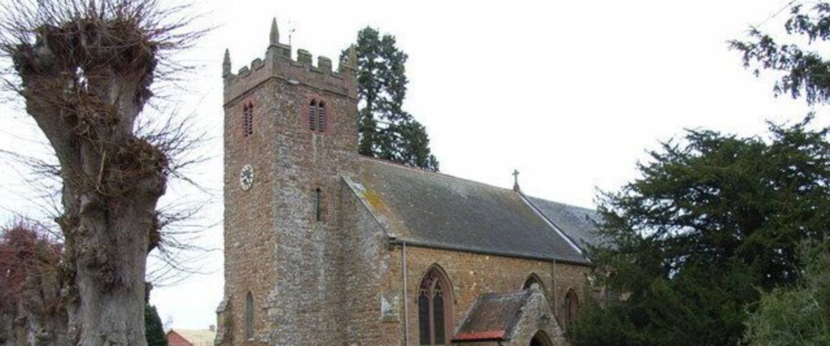 A historic church with a tall tower and a graveyard with headstones.