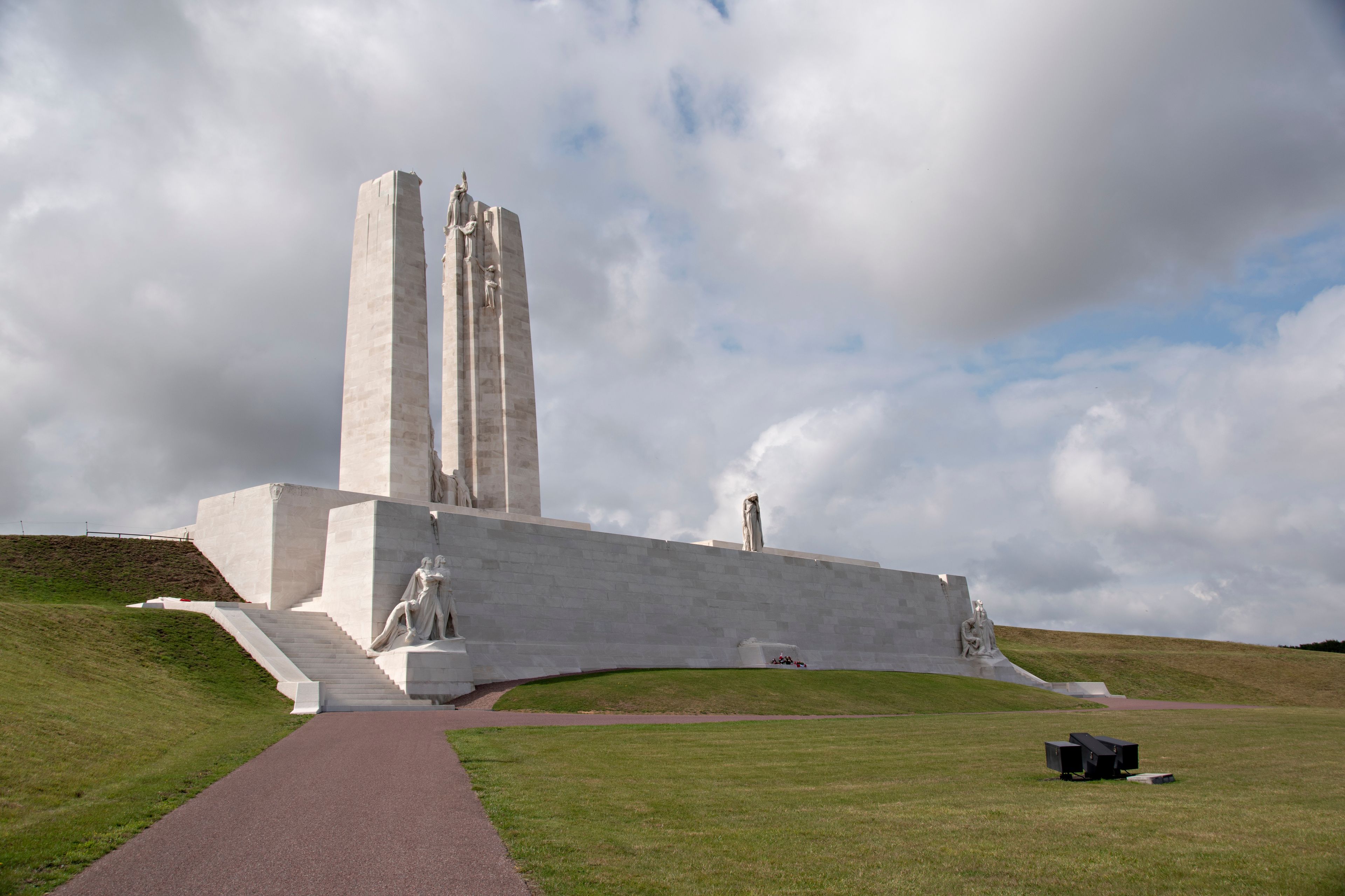 Ein großes, weißes Denkmal mit einer hohen zentralen Säule und Statuen am Fuß.