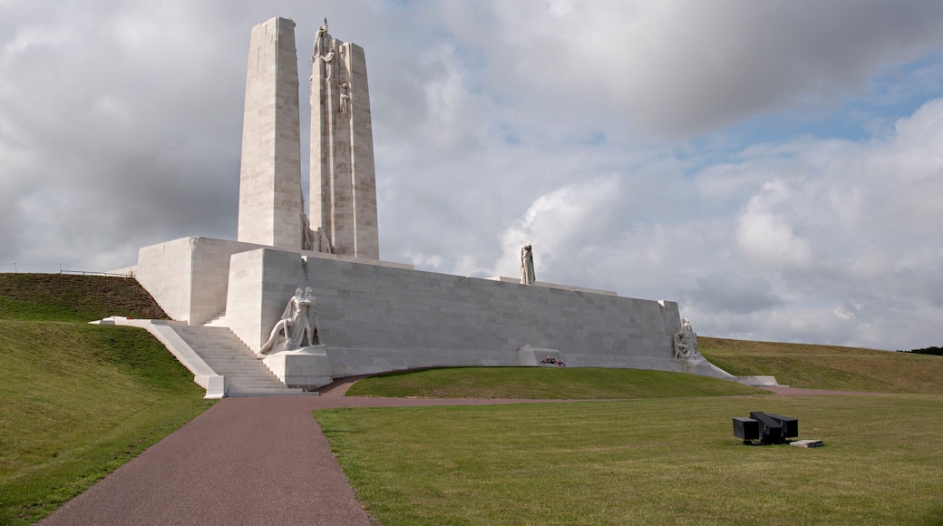 Ein großes, weißes Denkmal mit einer hohen zentralen Säule und Statuen am Fuß.