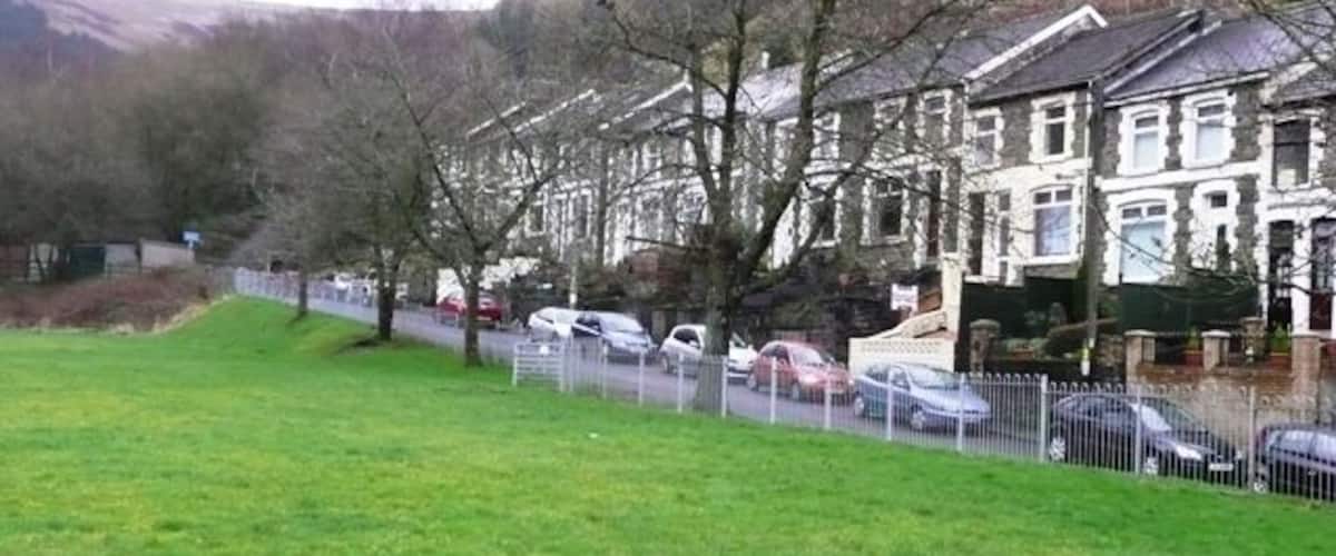 A grassy field with houses and parked cars.